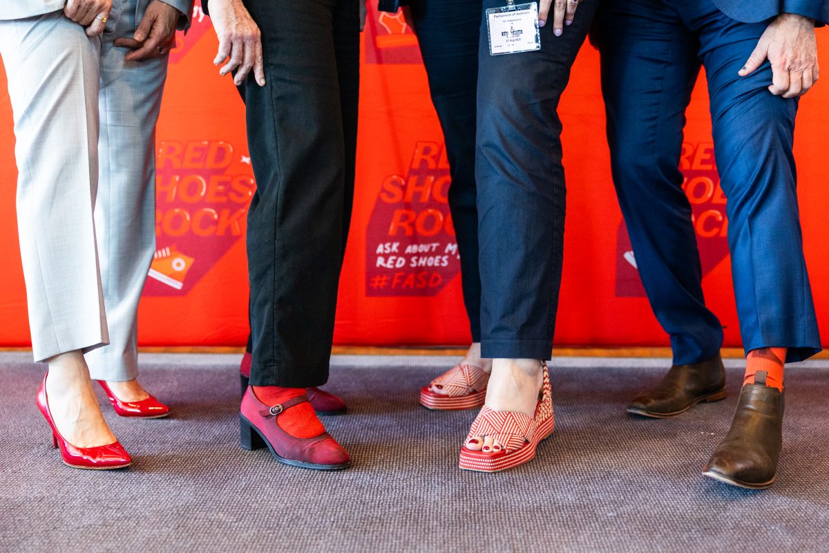 Four people's legs, wearing red shoes and socks.