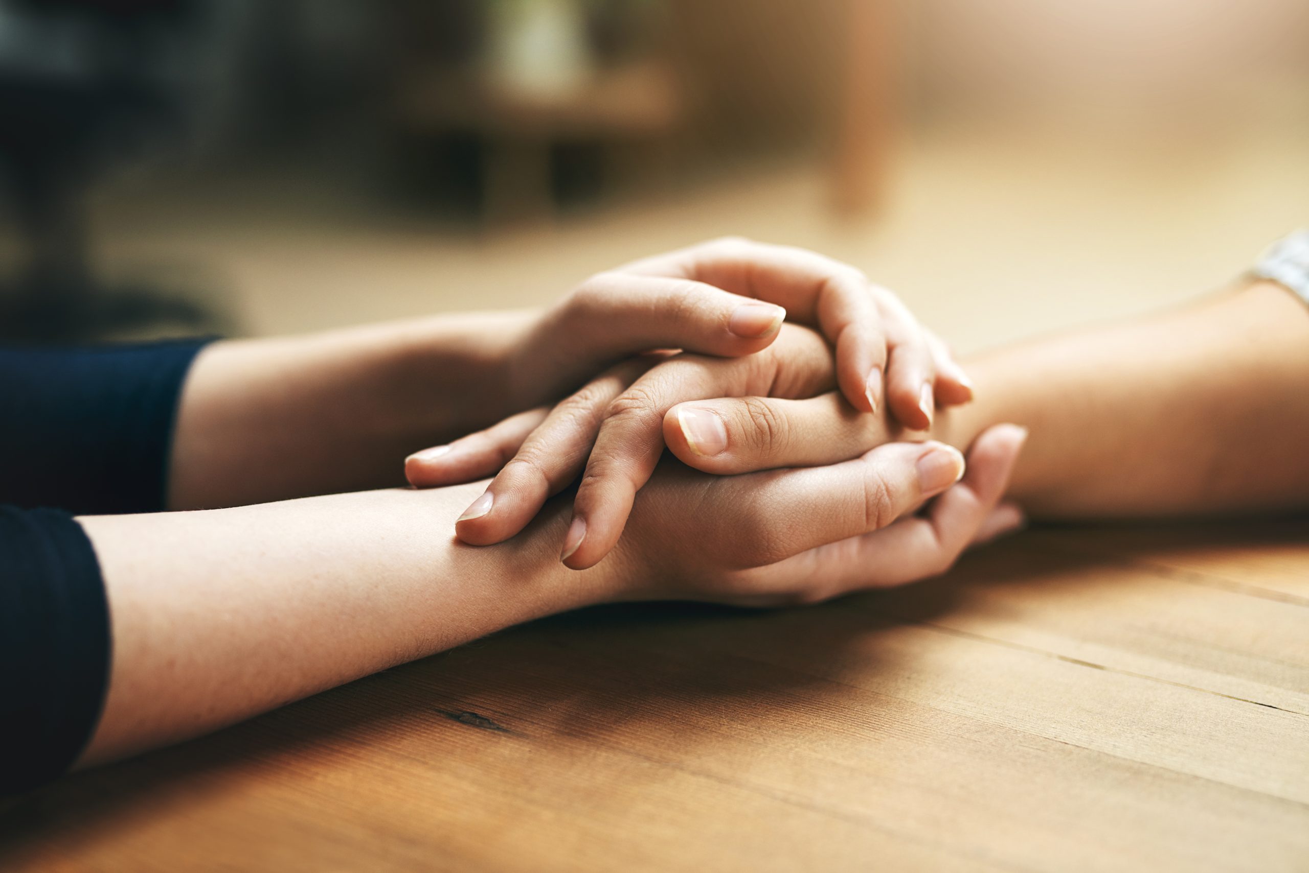 Two people clasp their hands together, in a show of support.