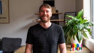 A white man in his 30s with a beard smiling.