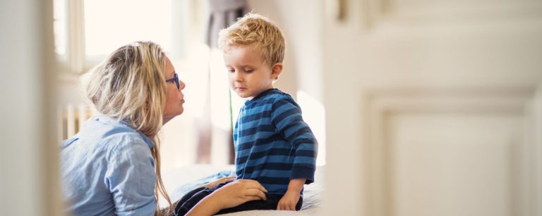 A mum crouching in front of her young son comforting him.