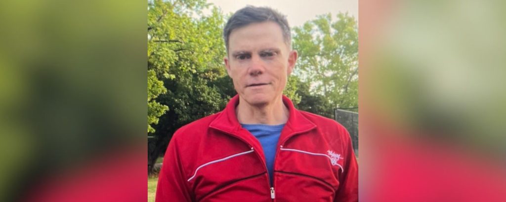 William, in a red jumper, standing in his backyard.