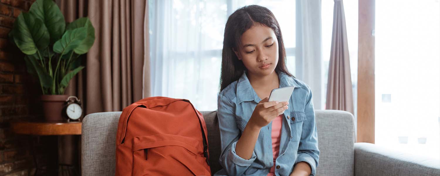 Teenage girl using her smartphone in her room
