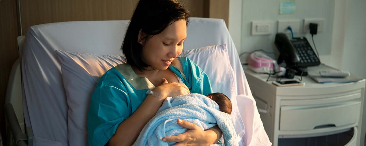 Mother breastfeeding her newborn baby in a hospital bed
