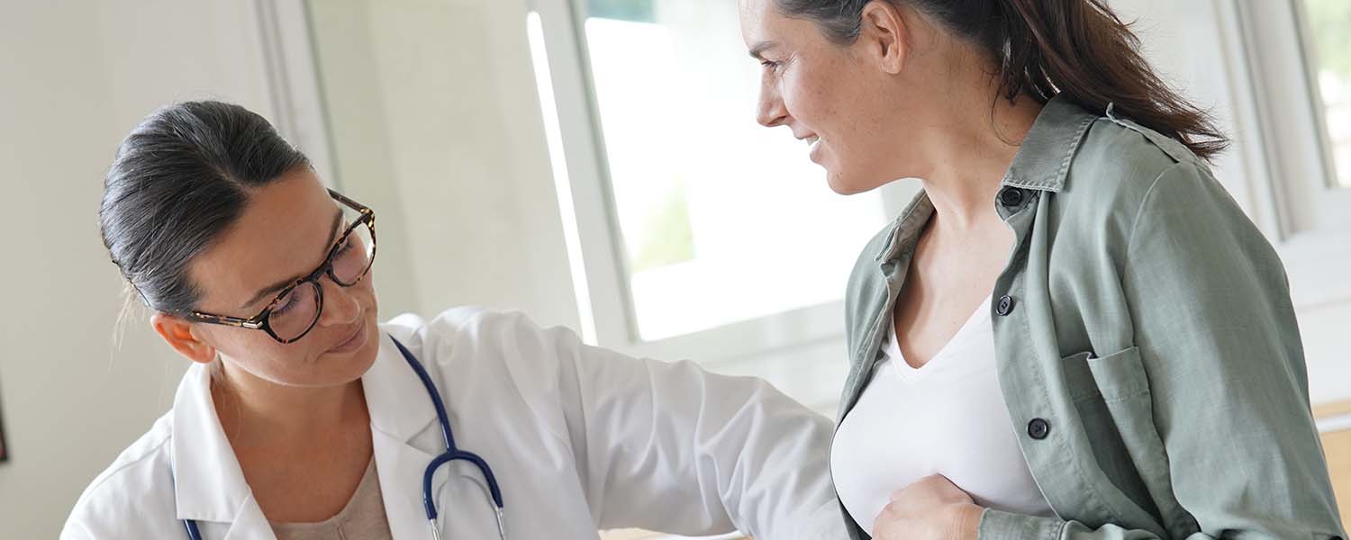 Healthcare professional touching pregnant woman's abdomen