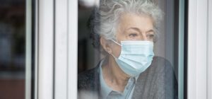 Elderly lady looking out of her window
