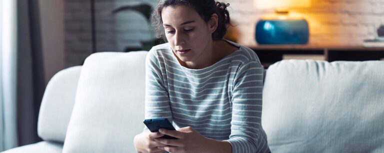 Woman sitting on couch looking at her mobile phone